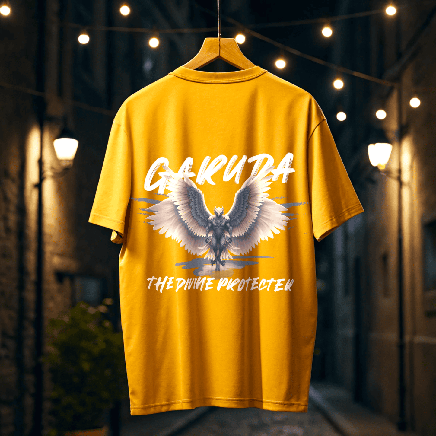 Golden Yellow t-shirt with garuda design and garuda the divine protecter text on a hanger against a blurred background of urban street By OFF THE RACK.