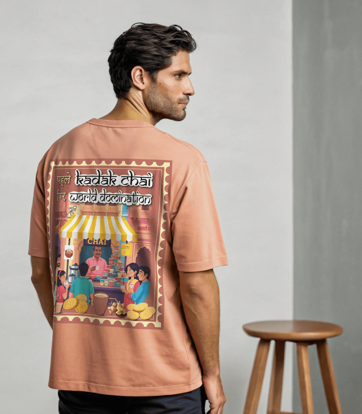 Man wearing Coral t-shirt with a graphic design of Kadak Chai on the back, standing against a plain background By OFF THE RACK