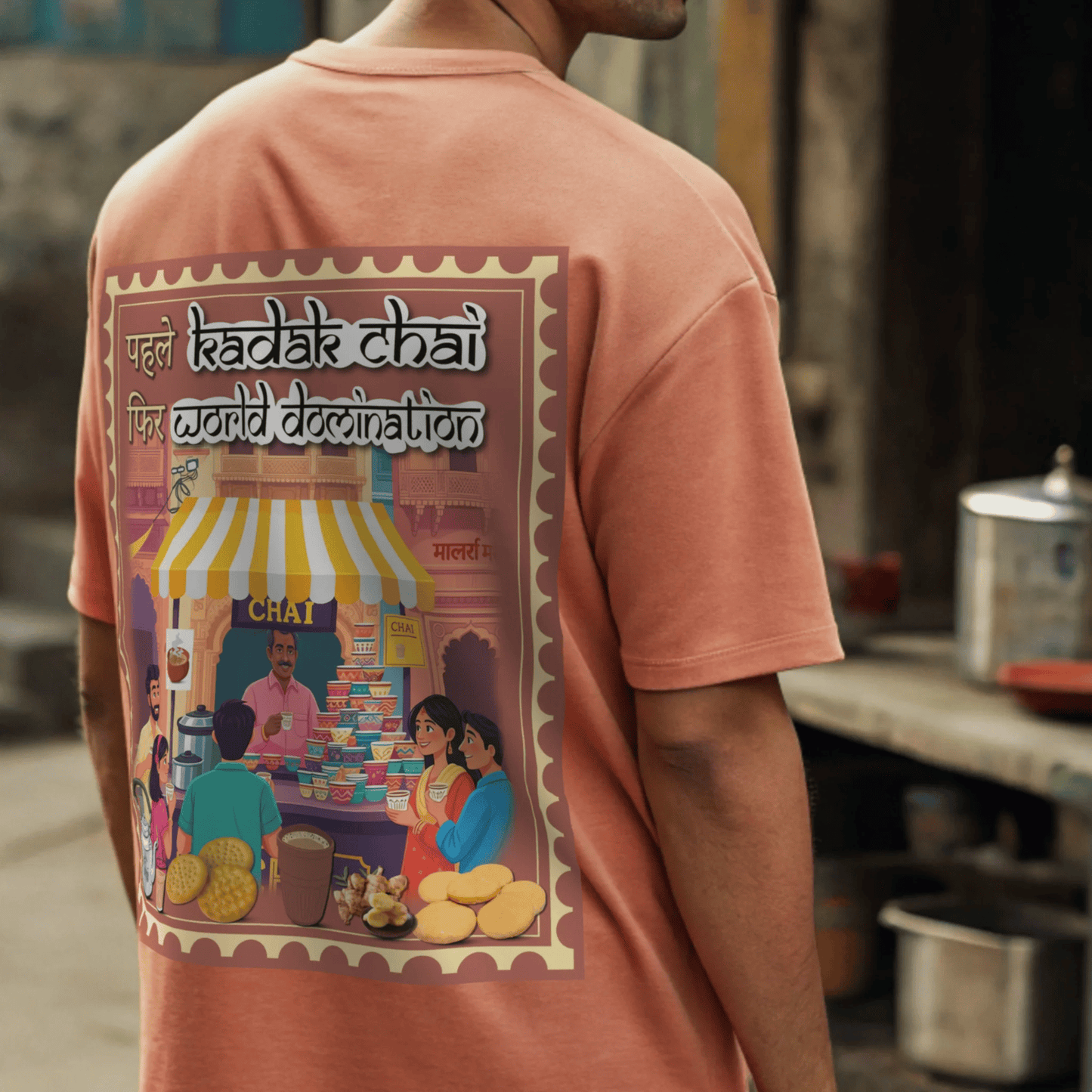 Person wearing a t-shirt with a colorful graphic design on the back, featuring text and images of people around a chai stall By OFFF THE RACK