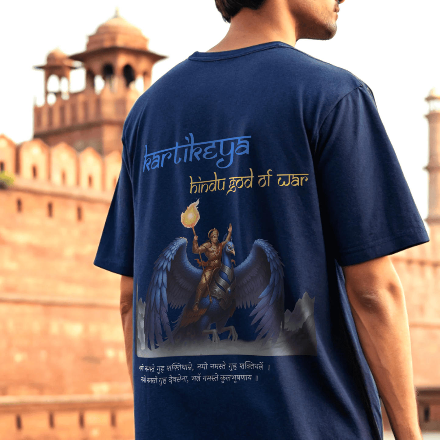 male model wearing a royal blue t-shirt with an illustration and text in front of a historical building By OFF THE RACK
