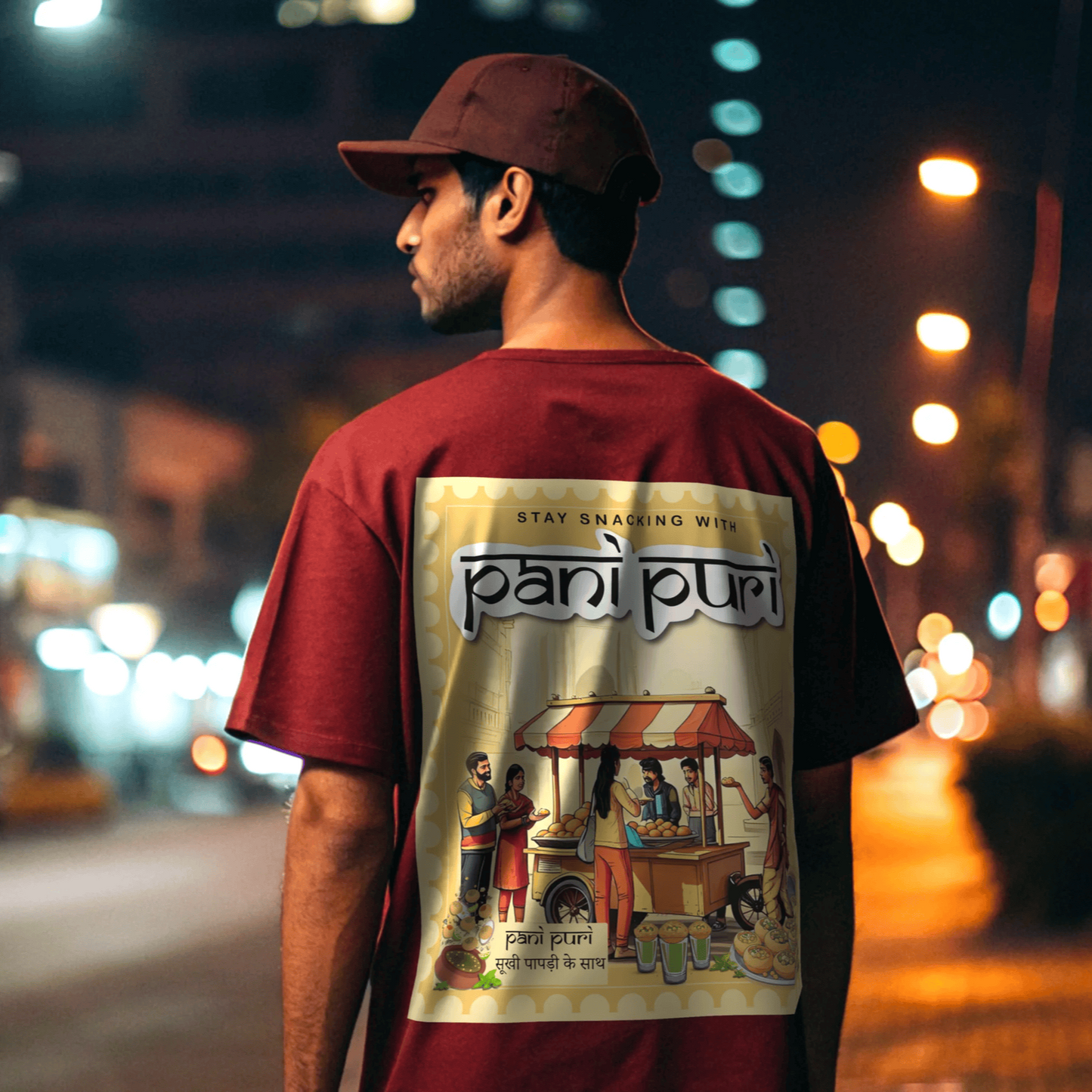 Model wearing a Red t-shirt with 'pani puri' design on the back, standing on a street at night By OFF THE RACK