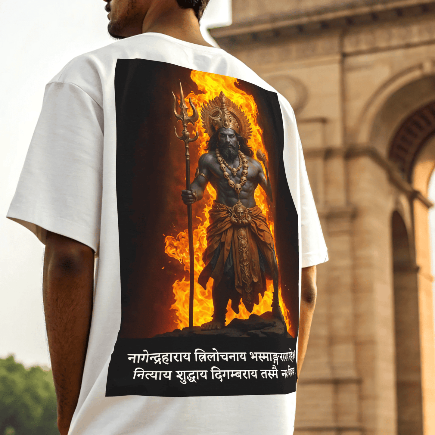 Person wearing a white t-shirt with a graphic design of shiva on fire, standing in front of historical building by OFF THE RACK