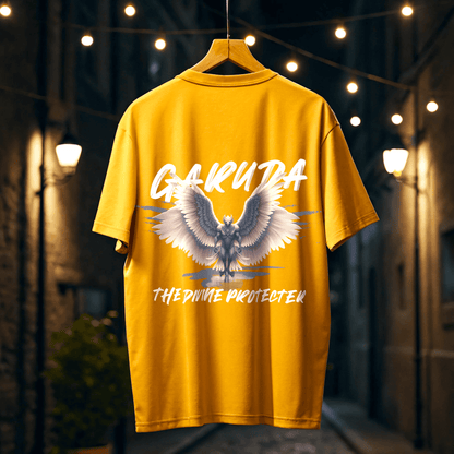 Golden Yellow t-shirt with garuda design and garuda the divine protecter text on a hanger against a blurred background of urban street By OFF THE RACK.